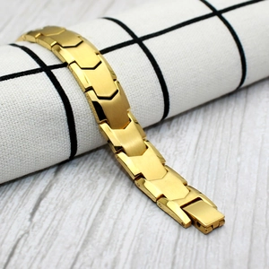 Detail of golden herringbone bracelet featuring brushed metal segments and folding clasp