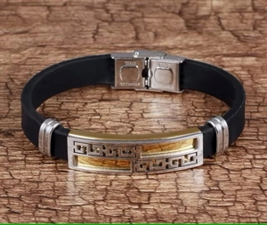 Macro shot of men's silicone bracelet showing gold Greek pattern and stainless steel clasp