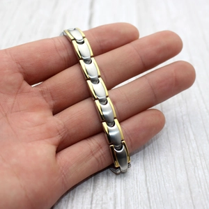 Macro detail of two-tone gold and silver bullet titanium steel magnetic therapy bracelet