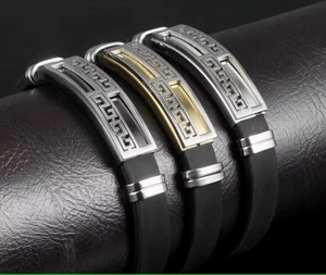 Macro detail of men's silicone bracelets with silver and gold Greek key metal plates