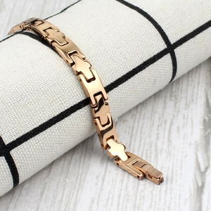 Détail du bracelet de santé en or rose avec maillons en croix sur tissu noir et blanc