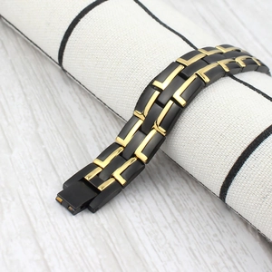 Detail of magnetic therapy bracelet with black and gold links on a white textured roll