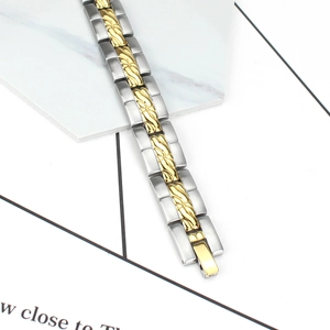 Detail eines zweifarbigen Edelstahl-Magnetarmbands mit goldgravierten Gliedern und Faltschließe