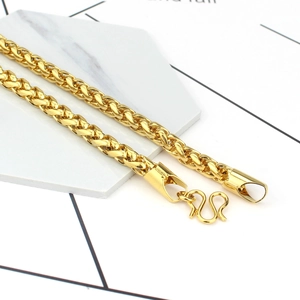 Polished 24K gold plated braided twist necklace with classic M-clasp on marble background