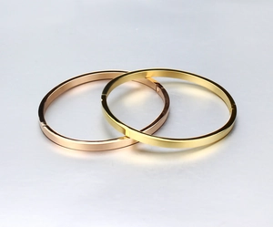Close-up of interlocking polished gold and rose gold titanium steel bangles with mirror finish