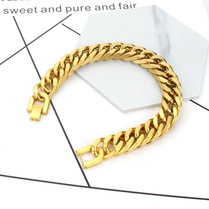 Close-up of golden Cuban link bracelet with fold-over clasp on marble surface