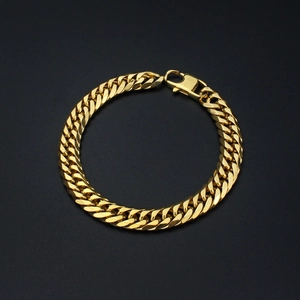 Macro detail of golden Cuban link bracelet with lobster clasp on black background