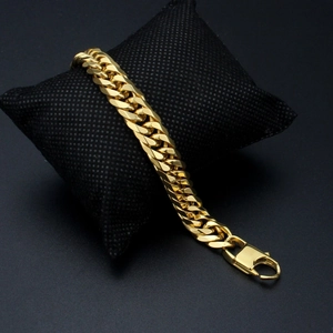 Polished gold Cuban link chain bracelet for men with secure lobster clasp on black cushion