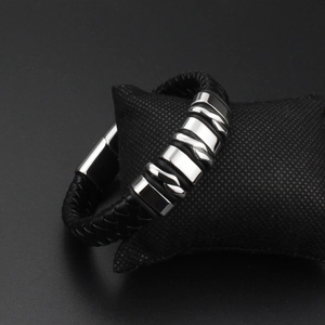 Men's punk black braided leather bracelet with polished steel buckle on a black cushion