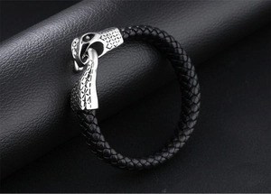 Detail of a braided black leather bracelet with a vintage eagle head metal clasp
