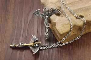 Detailed dragon wing and sword pendant on rustic wood surface with vintage fantasy style