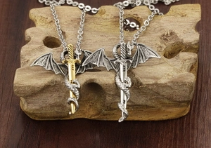 Detailed view of dragon-wrapped sword pendants in gold and silver on wood blocks