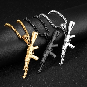Nahaufnahme von Gewehr-Anhängern in Gold, Schwarz und Silber mit Box-Halskette