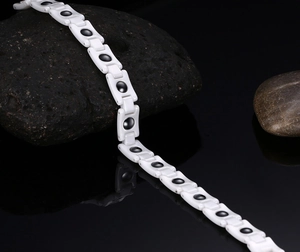 Detailed view of white ceramic magnetic bracelet with black round stone inlays