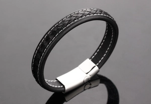 Macro view of men's black braided leather bracelet with silver buckle and white stitching