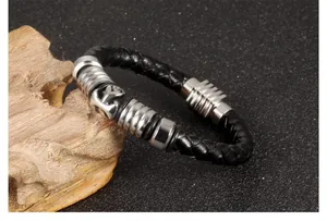 Detail of black braided leather bracelet with silver anchor charm and magnetic clasp
