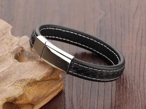 Detail of black braided leather men's bracelet with white stitching and silver magnetic clasp