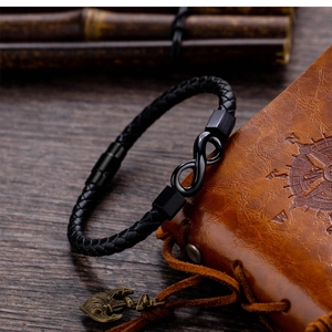 Detail of black braided leather infinity bracelet with matte magnetic clasp on wood