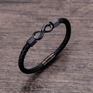 Macro detail of black braided leather bracelet featuring a metal infinity symbol and magnetic clasp