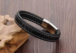Detail of black braided leather bracelet with white contrast stitching and silver magnetic clasp