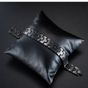 Detail of black stainless steel H-link chain bracelet on a leather cushion for men