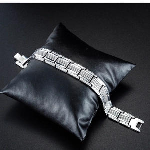 Macro view of silver steel link bracelet showing textured geometric checkered patterns