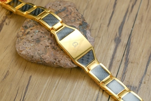 Gros plan détaillé du symbole maçonnique gravé sur un bracelet en or et fibre de carbone