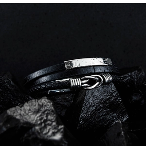 Detail of waterproof black multi-layer braided leather bracelet with silver metal clasp