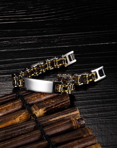 Detailed shot of two-tone steel motorcycle chain bracelet with blank metal plate on wood