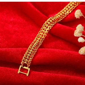 Détail d'un bracelet tressé doré avec fermoir carré sur tissu velours rouge