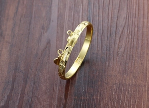 Detailed view of a gold-plated bracelet with starburst engraving and heart pendant