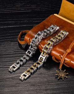 Detail of biker chain bracelets in silver and gold steel on a leather notebook