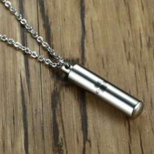 Stainless steel pet cremation urn necklace with laser engraved paw print on wood surface