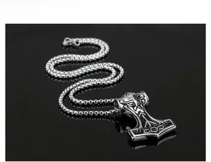 Macro detail of Mjölnir pendant with intricate Viking totems on a stainless steel box chain