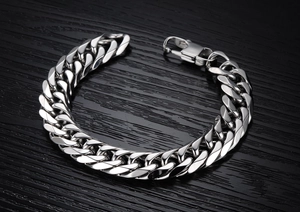Détail d'un bracelet gourmette argenté avec fermoir mousqueton sur fond en bois noir