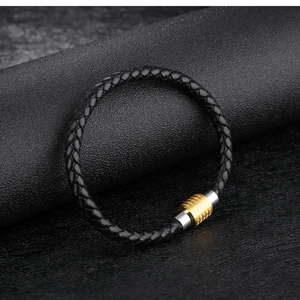 Dettaglio del bracciale in pelle intrecciata nera con chiusura magnetica in metallo inciso