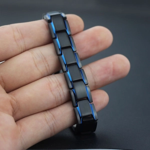Close-up of men's matte black and blue magnetic steel link bracelet held by hand