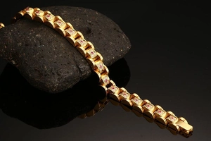 Macro detail of gold link bracelet with ruby stones and white zircon floral accents