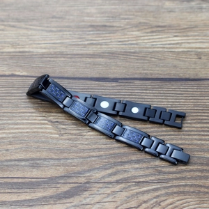 Pulsera magnética de acero inoxidable negro con fibra de carbono azul sobre madera