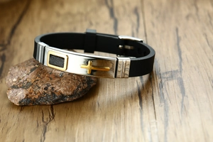 Détail d'un bracelet homme en silicone noir avec croix dorée sur plaque en acier inoxydable