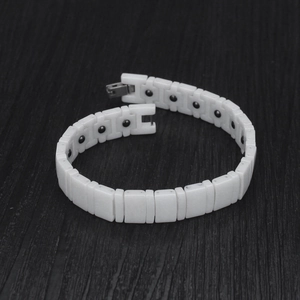 Détail d'un bracelet magnétique en céramique blanche avec inserts noirs sur bois noir