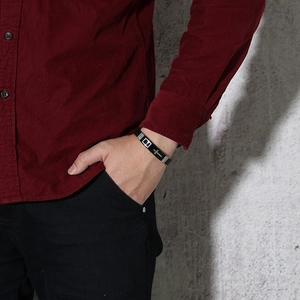 Bracelet homme en silicone noir avec croix en argent porté sur une tenue décontractée