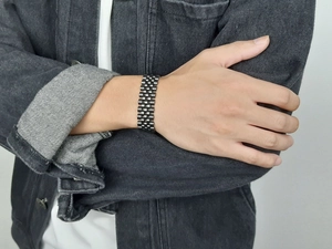 Détail du bracelet gourmette en acier inoxydable noir mat au poignet avec veste en jean