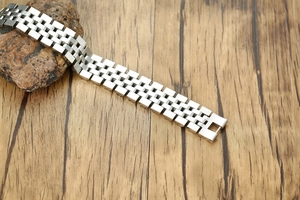 Détail d'un bracelet de montre Jubilee en acier inoxydable argenté sur bois et pierre