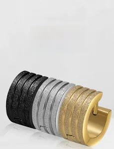Détail de créoles en acier mat noir, argent et or avec une texture rainurée