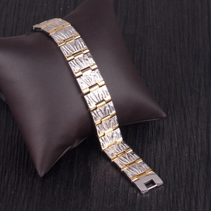 Detail of two-tone magnetic bracelet with engraved texture on brown leather display pillow