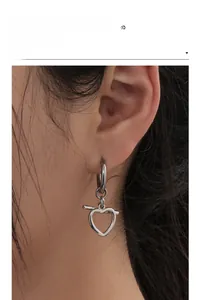 Close-up of heart-shaped hollow earrings in silver stainless steel on a female model