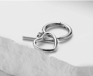 Macro view of silver heart earring component on stone stand with metallic luster