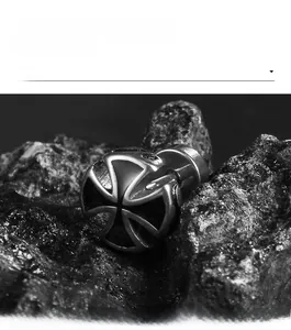 Macro shot of a gothic style cross stud earring on a black textured rock surface