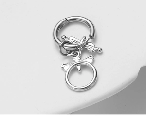 Vue macro détaillée du pendentif libellule en argent sur une créole en acier inoxydable